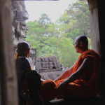 Due monaci osservano le facce in pietra dei Buddha a Angkor Thom