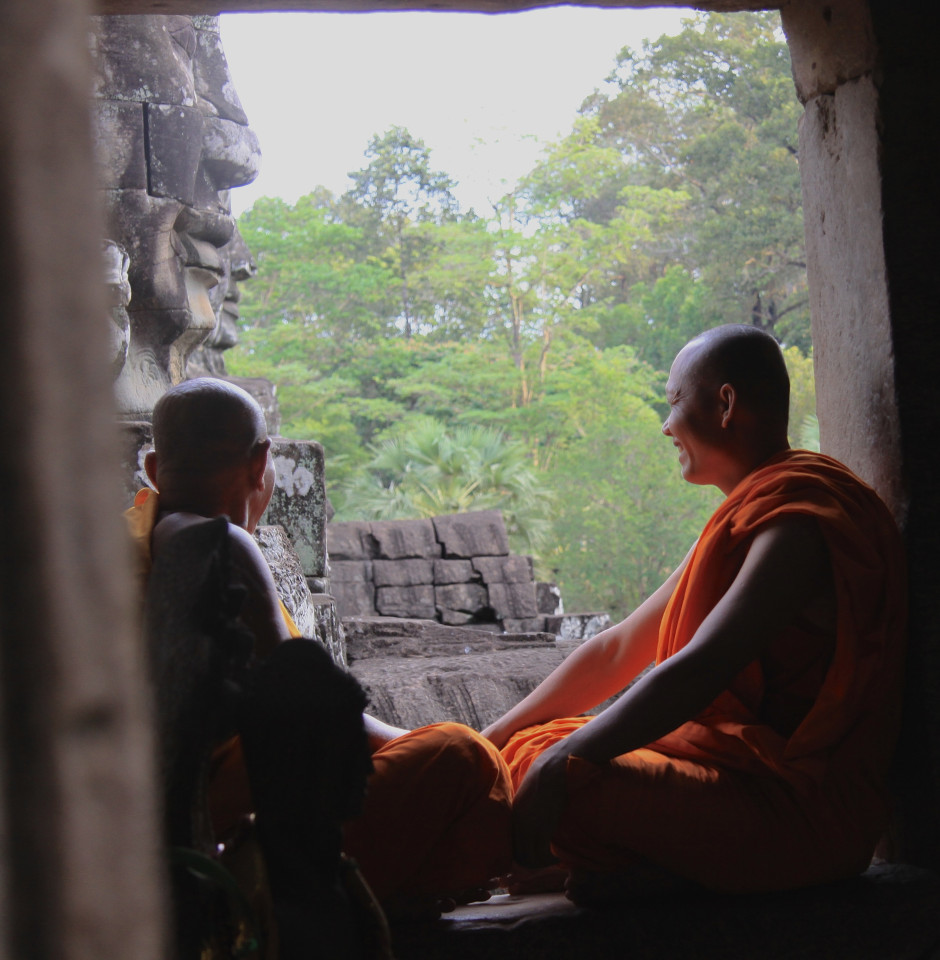 Due monaci osservano le facce in pietra dei Buddha a Angkor Thom